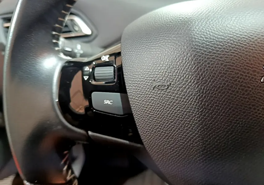 Gros plan sur le volant cuir noir de la Peugeot 308 Puretech 110 S&S Style, avec commandes audio intégrées.