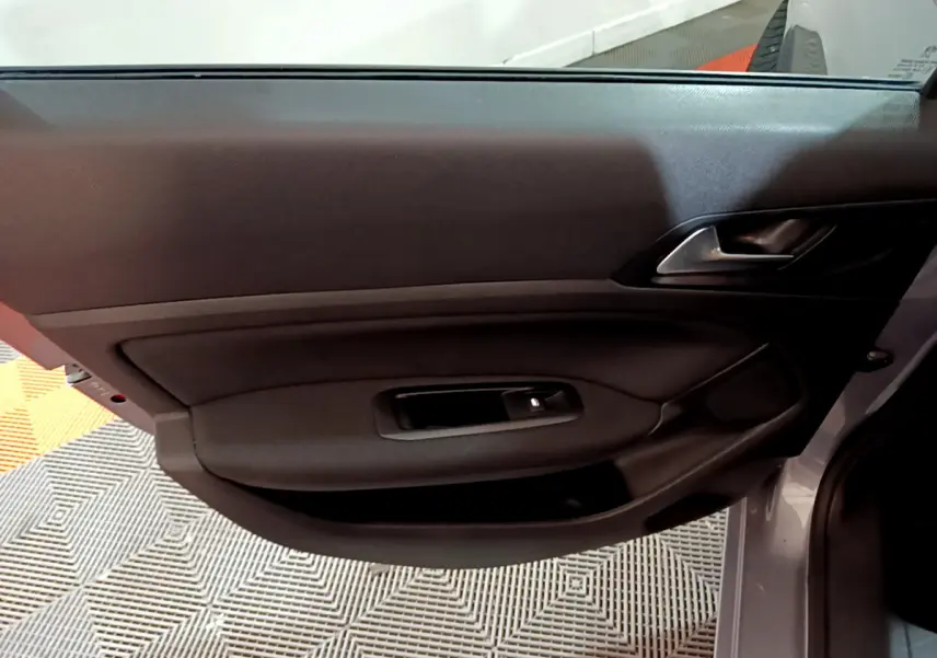Porte intérieure côté gauche de la Peugeot 308 gris clair, avec poignée et commande de lève-vitre intégrée.