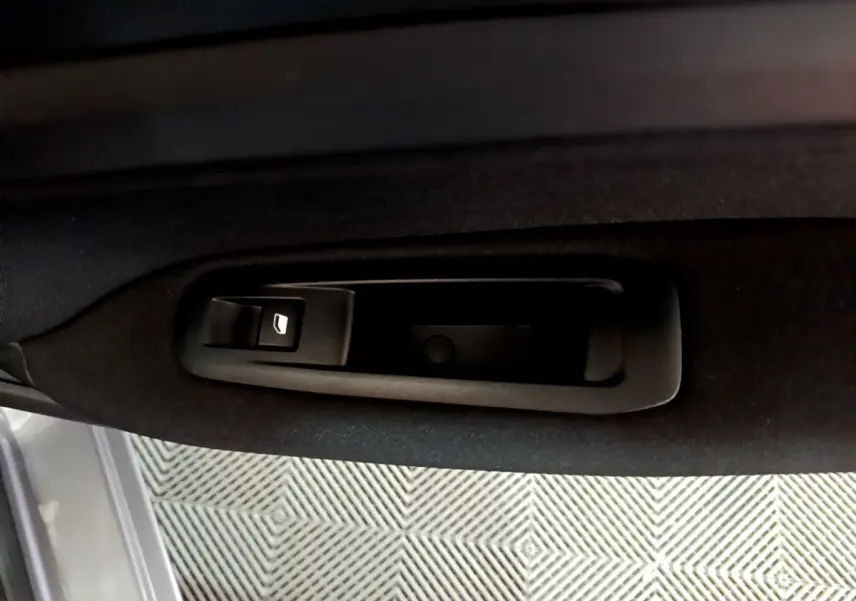 Détail de la commande de lève-vitre sur la porte intérieure côté conducteur d'une Peugeot 308 gris clair 2020.