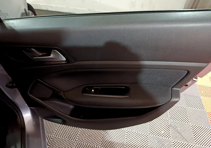 Vue rapprochée de la porte avant gauche gris clair de la Peugeot 308 Puretech 110 S&S Style avec poignée intérieure noire.