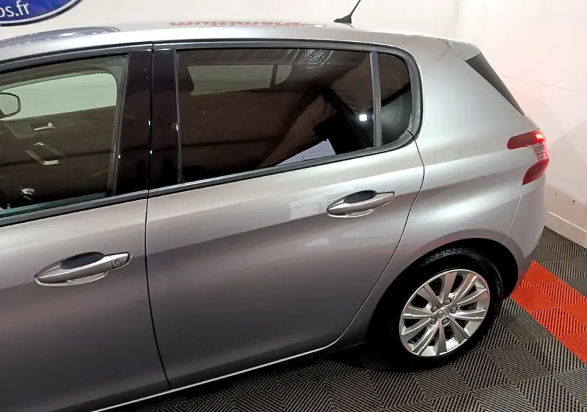 Vue latérale côté droit d'une Peugeot 308 gris clair, mettant en valeur les portes arrière et la roue arrière.