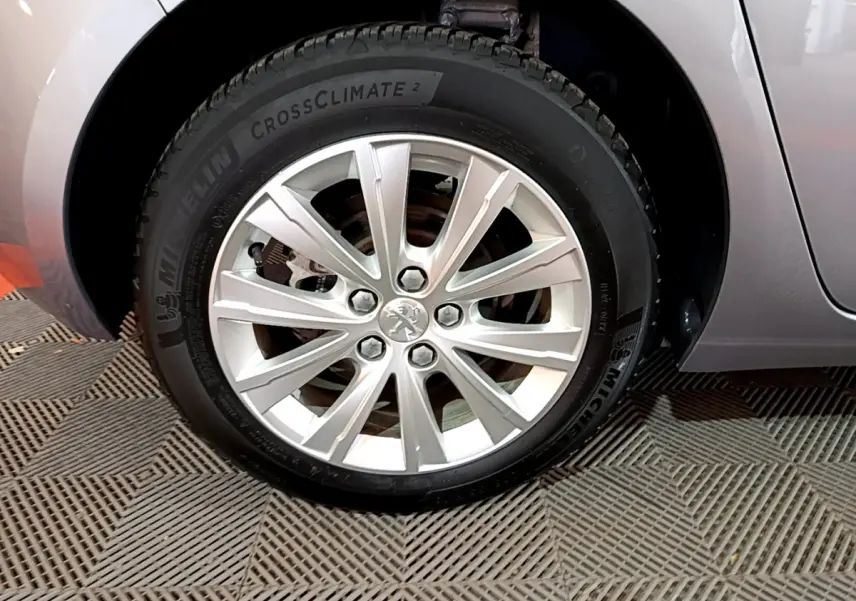 Gros plan sur la roue avant gauche grise d'une Peugeot 308 Puretech 110 S&S Style avec jante alliage argentée.