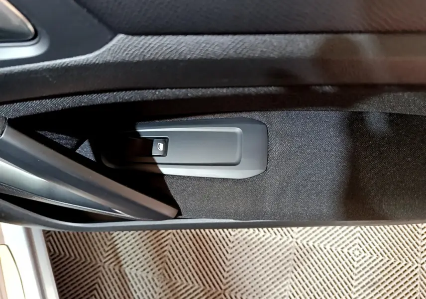 Bouton de commande de lève-vitre côté gauche dans l'habillage noir de la porte d'une Peugeot 308 gris clair 2020.