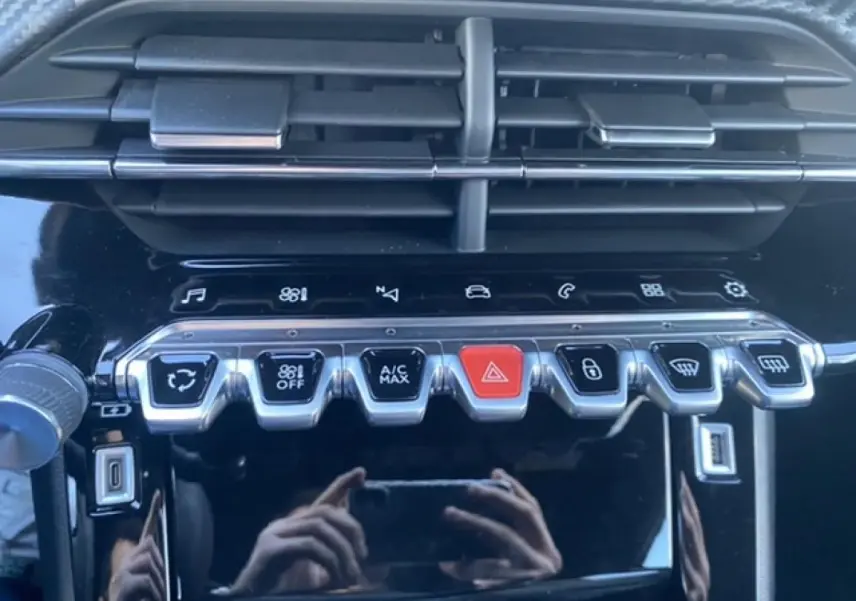 Gros plan sur la console centrale noire du Peugeot 2008 2021 avec boutons de climatisation et commandes tactiles.