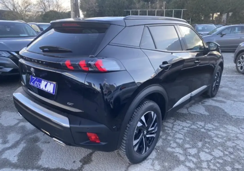 Vue 3/4 arrière droite d'un Peugeot 2008 noir brillant avec feux arrière à griffes et jantes alliage noires.