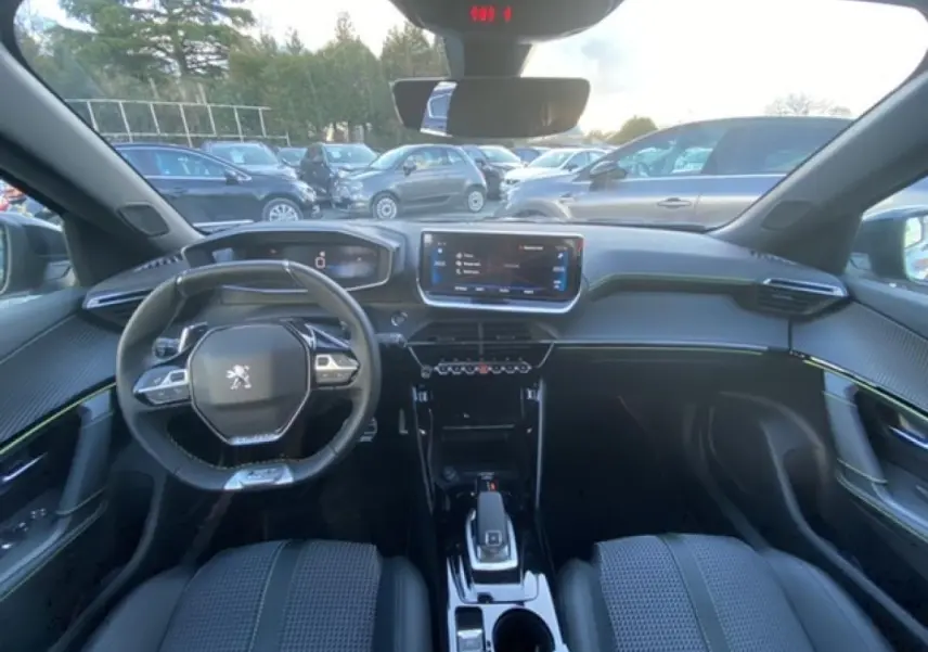 Intérieur Peugeot 2008 noir vue depuis l'arrière, tableau de bord moderne avec écran tactile et volant compact.