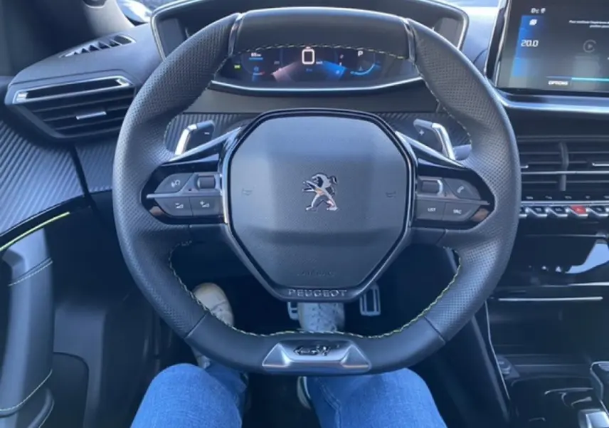 Vue intérieure centrée sur le volant noir du Peugeot 2008 2021, avec tableau de bord numérique et écran tactile à droite.