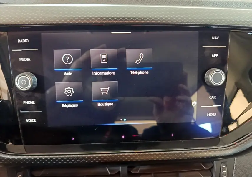 Écran tactile central du Volkswagen T-Cross gris foncé, affichant le menu principal avec options radio, téléphone et réglages.