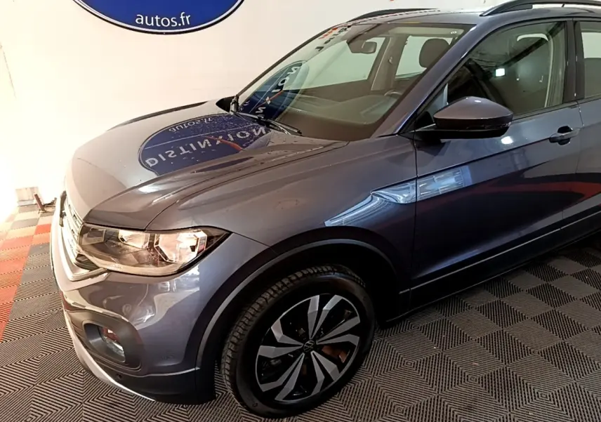 Vue 3/4 avant droit du Volkswagen T-Cross gris foncé 2023 avec jantes noires et toit noir.