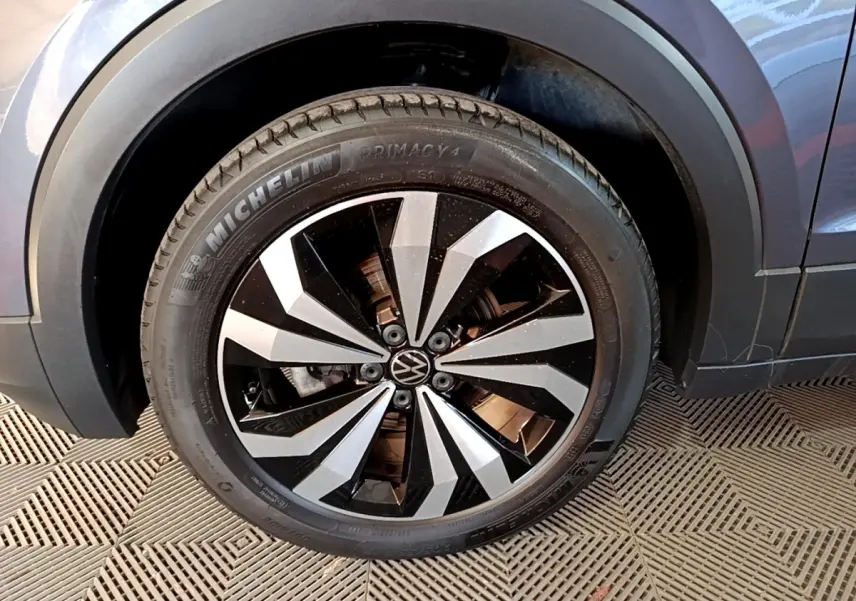 Gros plan sur la roue avant droite du Volkswagen T-Cross gris foncé, avec jante alliage bicolore et pneu Michelin.
