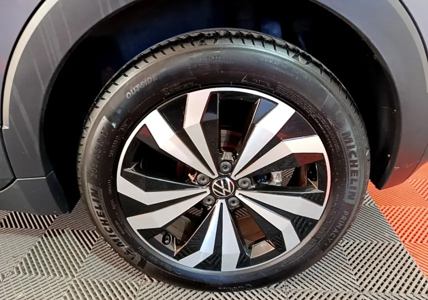 Gros plan sur la roue avant droite du Volkswagen T-Cross gris foncé avec jante alliage bicolore distinctive.
