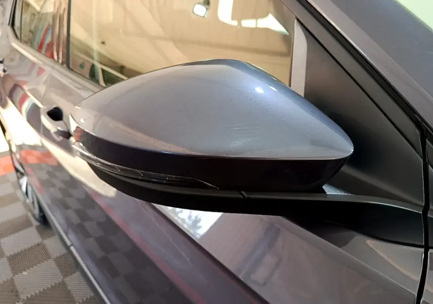 Rétroviseur côté gauche gris foncé du Volkswagen T-Cross 2023, avec poignée de porte visible en arrière-plan.