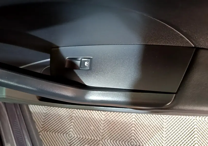 Détail du bouton de verrouillage des portes sur la portière intérieure côté conducteur du Volkswagen T-Cross gris foncé.