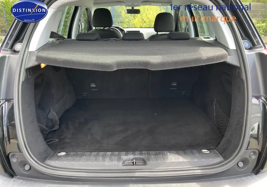 Coffre ouvert vu de l'arrière d'un Peugeot 2008 noir métal, montrant un espace de chargement propre et couvert.