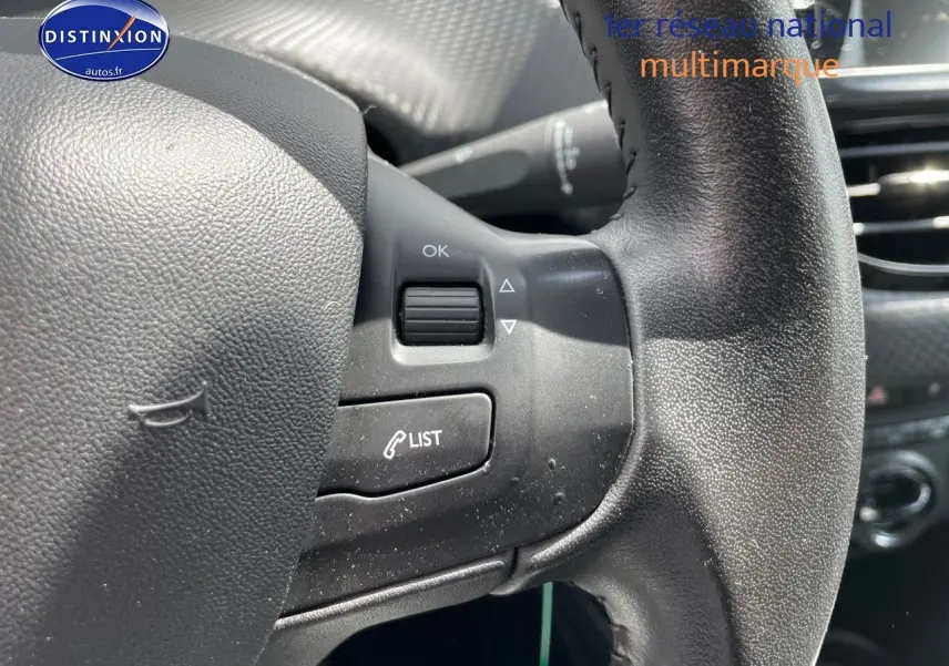 Gros plan sur le volant noir texturé du Peugeot 2008 1.2 PureTech 82ch Style, montrant les commandes intégrées côté gauche.