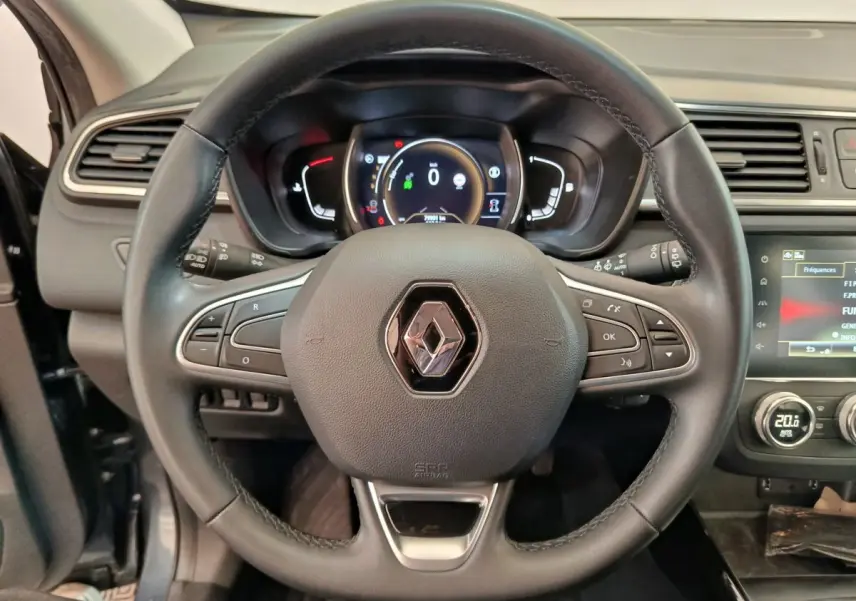Vue intérieure centrée sur le volant cuir noir du Renault Kadjar 2022 avec tableau de bord numérique et écran tactile.