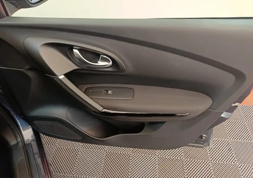 Intérieur de la porte côté gauche du Renault Kadjar gris foncé, avec poignée argentée et commande de vitre.