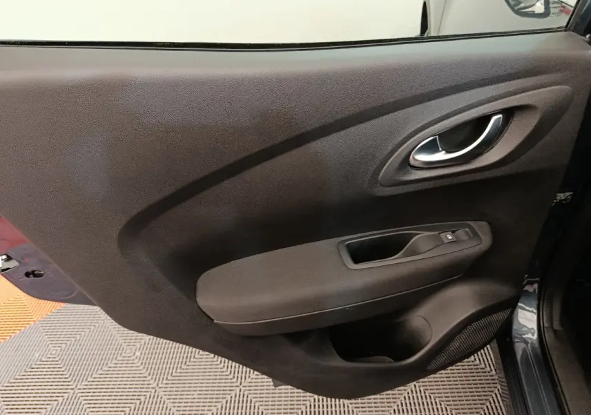 Vue rapprochée de la porte avant droite gris foncé du Renault Kadjar Business 2022 avec poignée intérieure chromée.