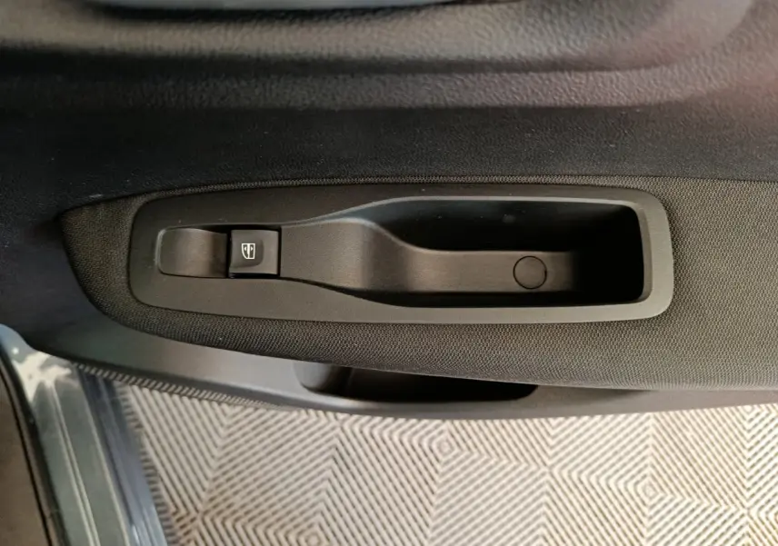 Poignée de porte intérieure noire côté gauche du Renault Kadjar Business 2022 avec bouton de commande de vitre électrique.