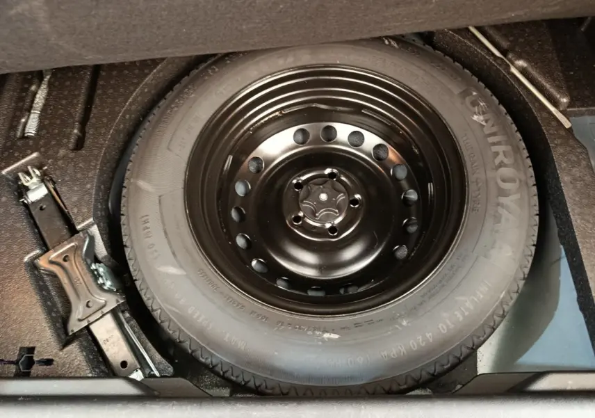 Gros plan sur la roue de secours noire et le cric dans le coffre d'un Renault Kadjar gris foncé 2022.
