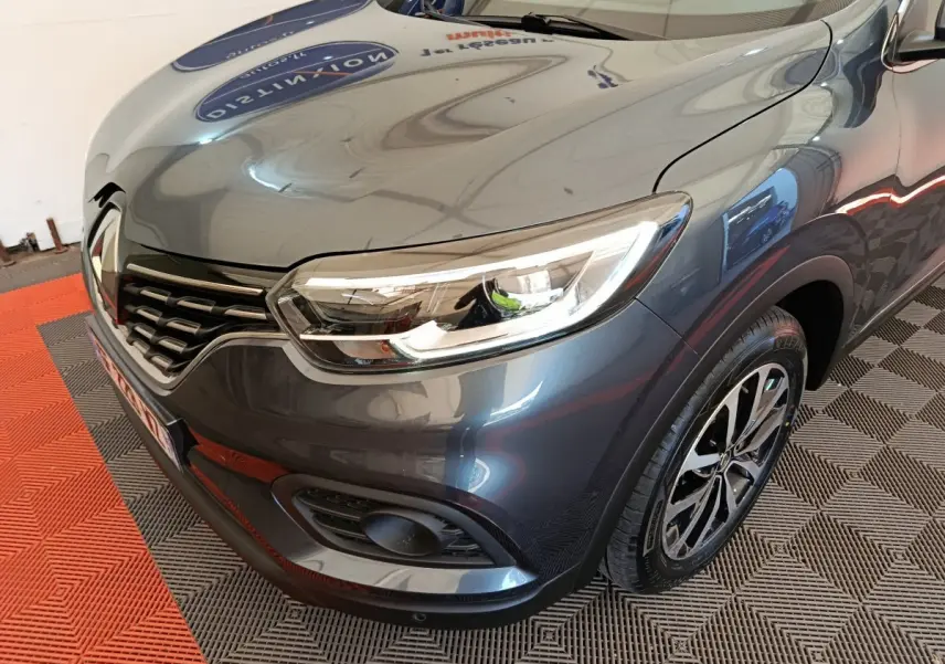Vue 3/4 avant droit d'un Renault Kadjar Business gris foncé avec phares LED et jantes alliage distinctives.