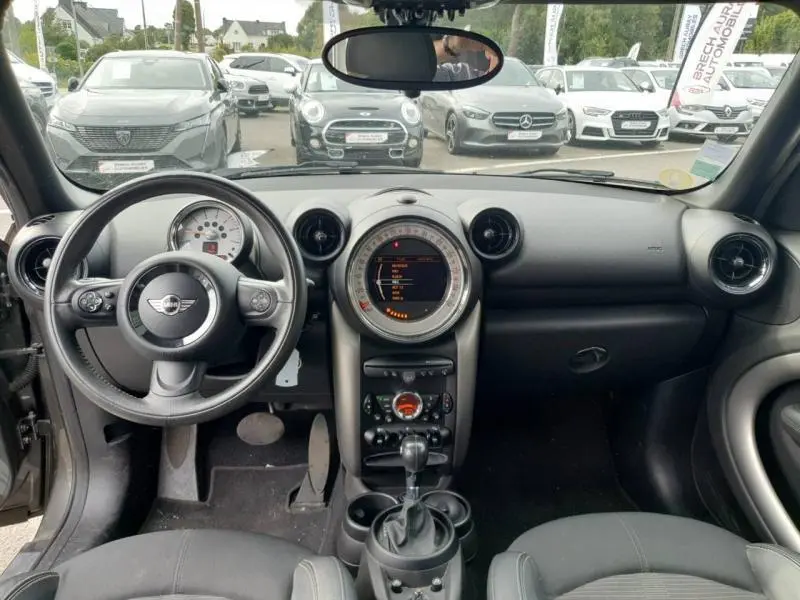 Intérieur de la MINI Countryman Cooper D 2014 vu de face, tableau de bord noir avec volant cuir et console centrale ronde.