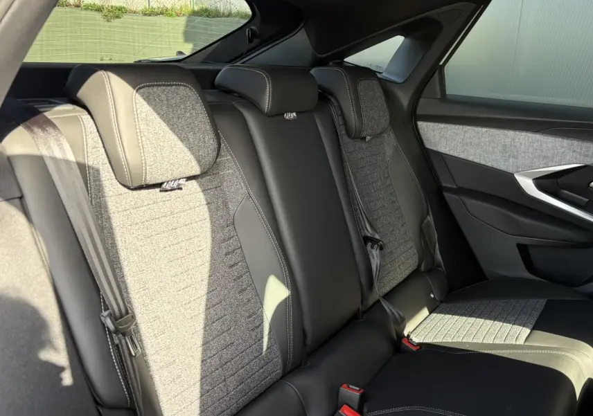 Vue latérale droite des sièges arrière gris et noirs du Peugeot 3008 Hybrid 145 e-DSC6 Allure, avec ceintures et appuie-têtes intégrés.