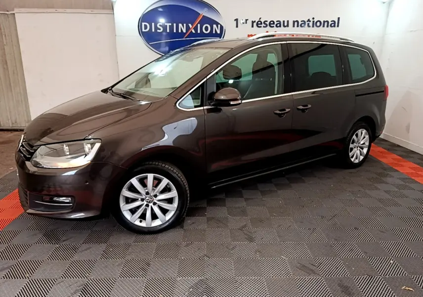 Vue de profil droit d’un Volkswagen Sharan marron 2017 dans un showroom avec jantes alliage et toit ouvrant.
