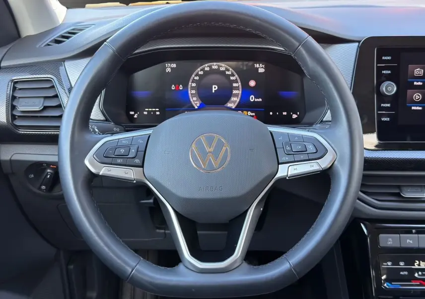 Vue rapprochée du volant cuir noir multifonction Volkswagen T-Cross 2025 avec tableau de bord digital et écran tactile.