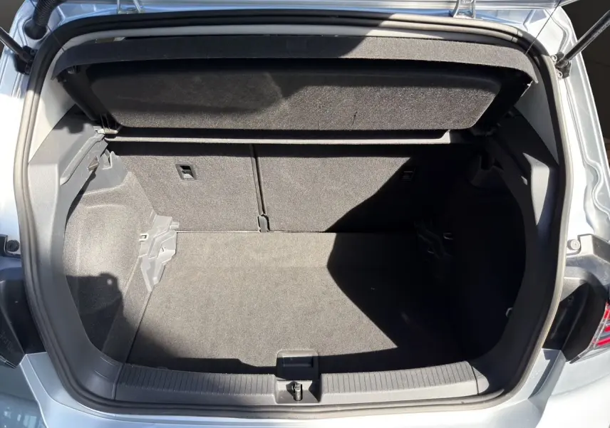Coffre ouvert vu de l'arrière d'un Volkswagen T-Cross 2025 couleur reflet d'argent, intérieur noir.