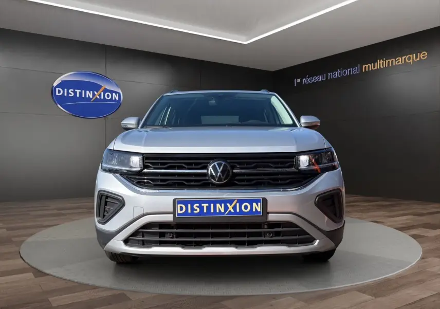 Volkswagen T-Cross 2025 couleur reflet d'argent vue de face en intérieur avec calandre noire et logo VW central.