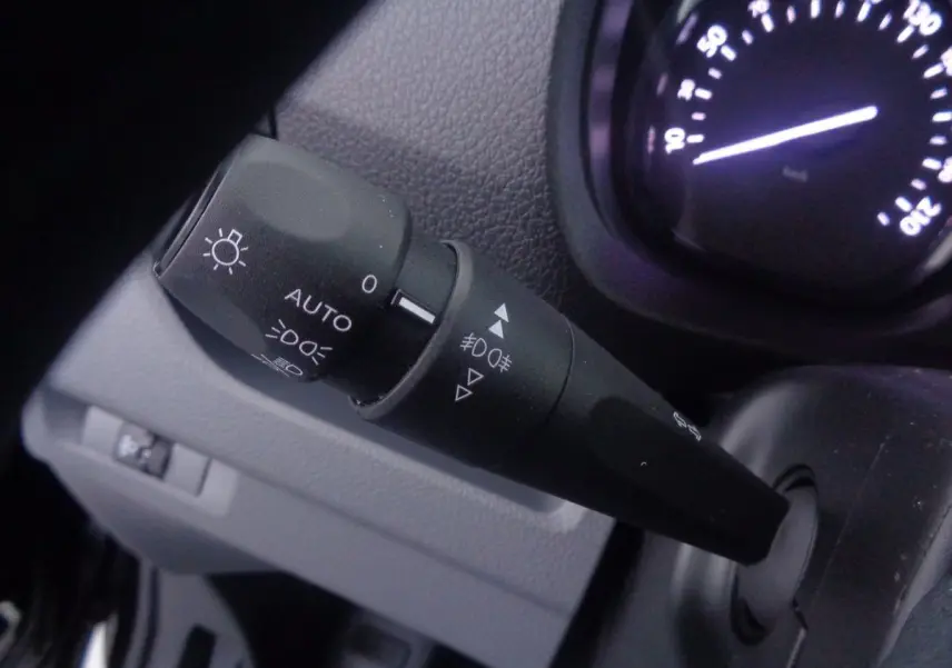 Gros plan sur la manette des phares et clignotants du Peugeot Expert Fourgon noir, tableau de bord partiellement visible.