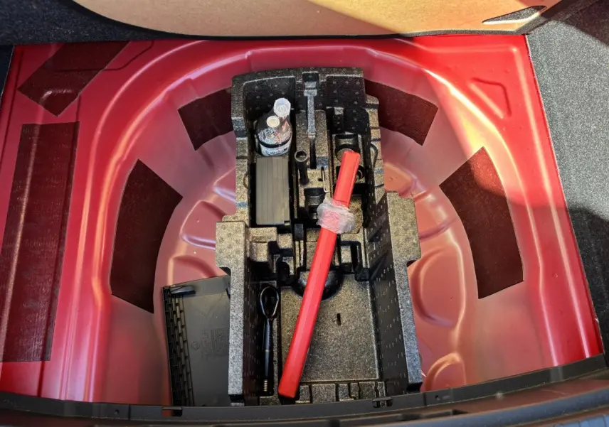 Coffre ouvert montrant le rangement sous plancher rouge velvet metal avec outils et triangle de sécurité SKODA SCALA 2024.