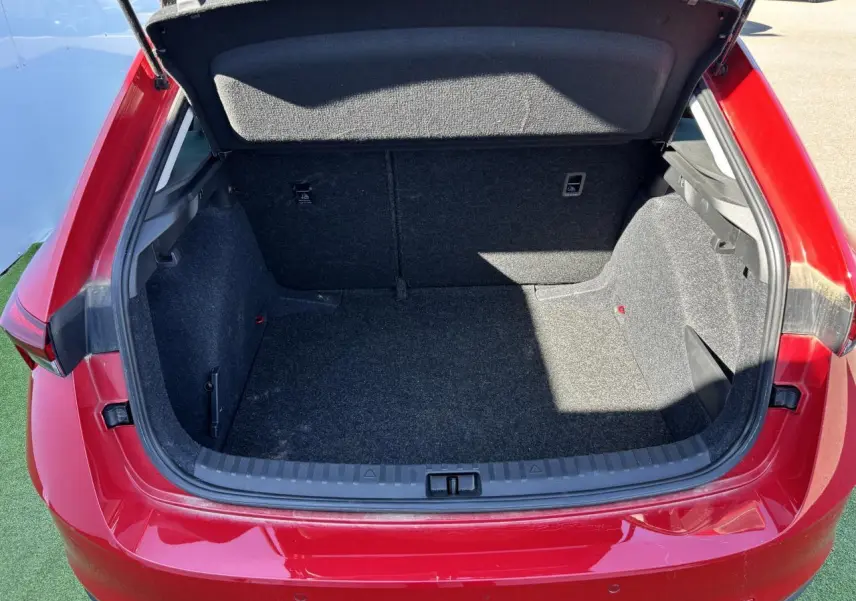 Coffre ouvert vu de l'arrière d'une Skoda Scala 2024 rouge Velvet Metal, montrant l'espace de chargement vide.
