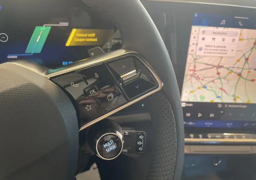 Gros plan sur le volant et le tableau de bord numérique du Renault Rafale 2025, avec écran tactile affichant une carte.