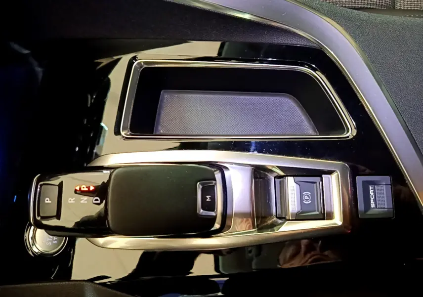 Vue rapprochée de la console centrale noire brillante du Peugeot 3008 gris clair avec levier de vitesse automatique et bouton Sport.
