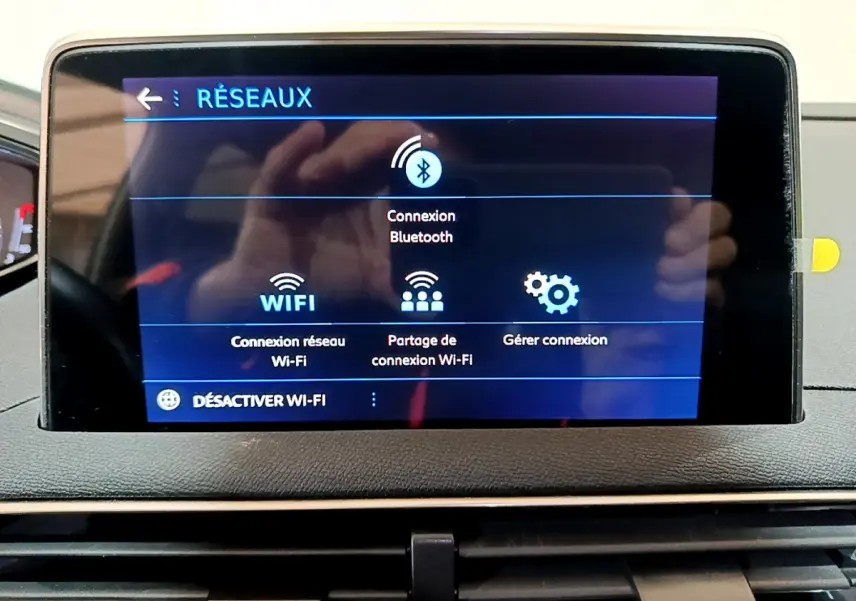 Écran tactile central affichant les options réseau Bluetooth et Wi-Fi dans le tableau de bord du Peugeot 3008 gris clair.