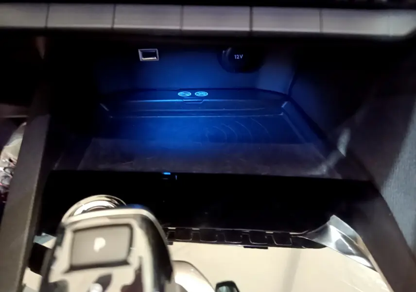 Gros plan sur la console centrale noire du Peugeot 3008 gris clair, avec prise 12V et port USB visibles.