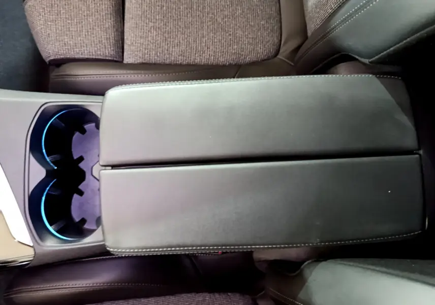 Accoudoir central en cuir noir avec porte-gobelets éclairés en bleu dans l'habitacle du Peugeot 3008 gris clair 2020.