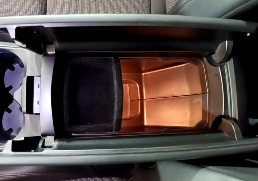 Vue plongeante sur le rangement central intérieur du Peugeot 3008 gris clair, avec compartiment ouvert et porte-gobelets à côté.