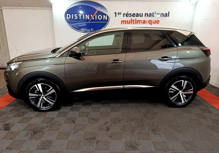 Profil côté gauche du Peugeot 3008 gris clair 2020 avec jantes alliage et toit noir contrasté dans un showroom.