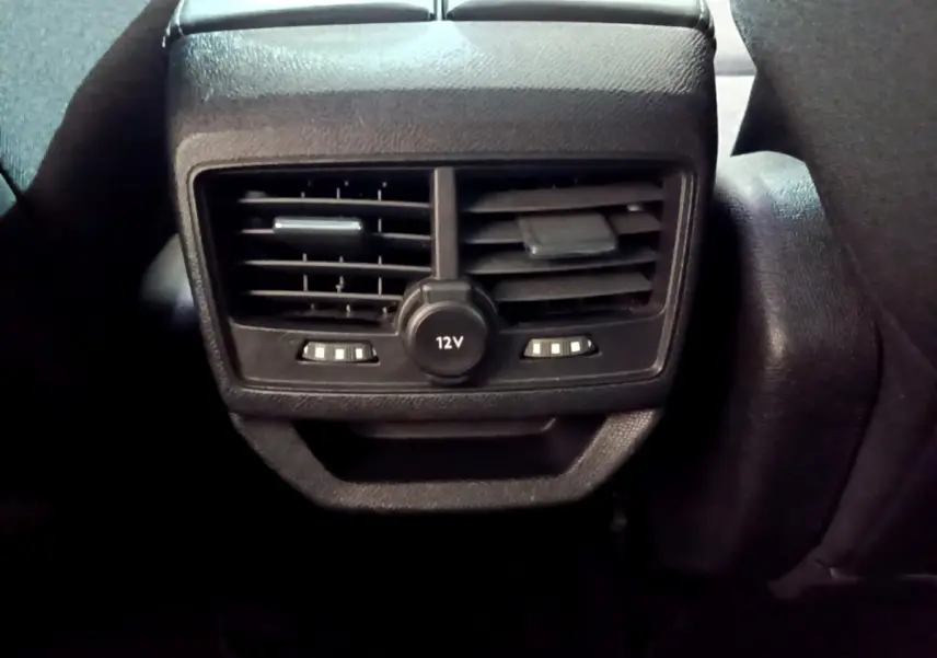 Gros plan sur la console arrière noire du Peugeot 3008 gris clair 2020, avec prises d'air et prise 12V visible.