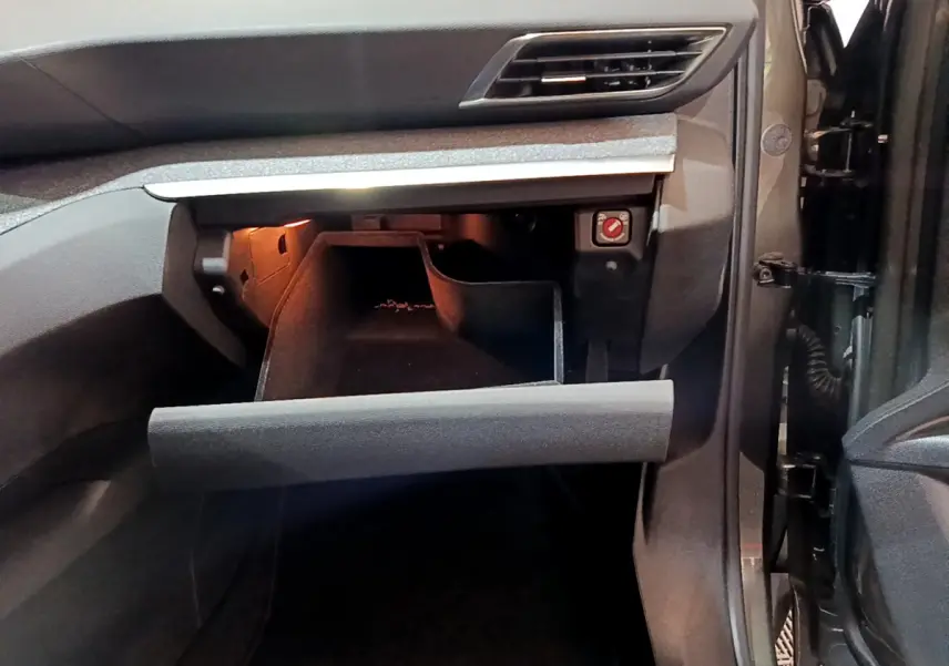Intérieur du Peugeot 3008 gris clair, vue sur la boîte à gants ouverte côté passager avec éclairage intérieur.