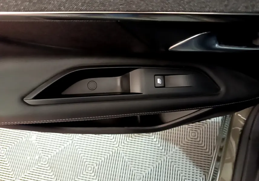 Détail de la commande de lève-vitre côté conducteur sur la porte intérieure noire du Peugeot 3008 gris clair 2020.
