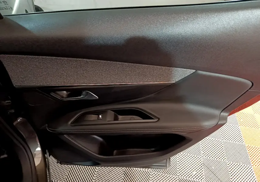 Vue rapprochée de la porte côté gauche du Peugeot 3008 gris clair, avec garniture noire et commandes de vitre intégrées.