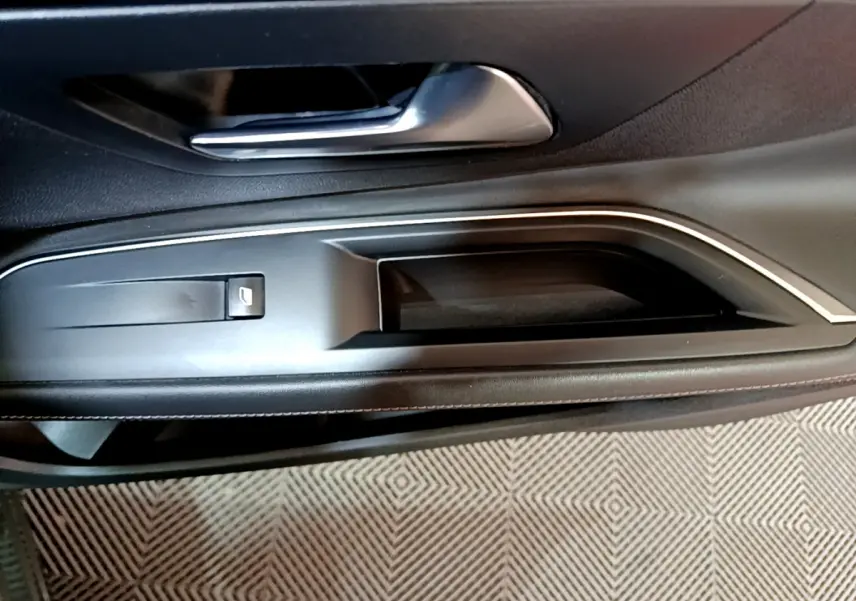 Poignée intérieure et commande de lève-vitre côté conducteur du Peugeot 3008 gris clair, finition Allure Business.