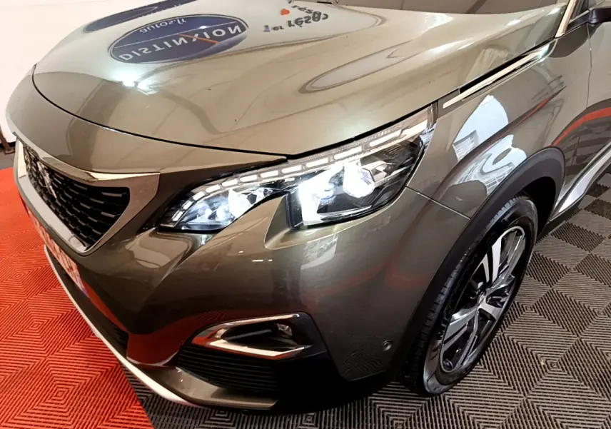 Vue 3/4 avant droit d'un Peugeot 3008 gris clair avec phares LED allumés et jantes alliage noires.