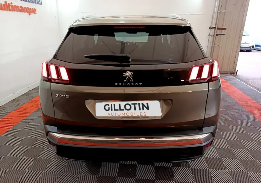 Vue arrière d'un Peugeot 3008 gris clair avec feux arrière LED caractéristiques et logo lion central.