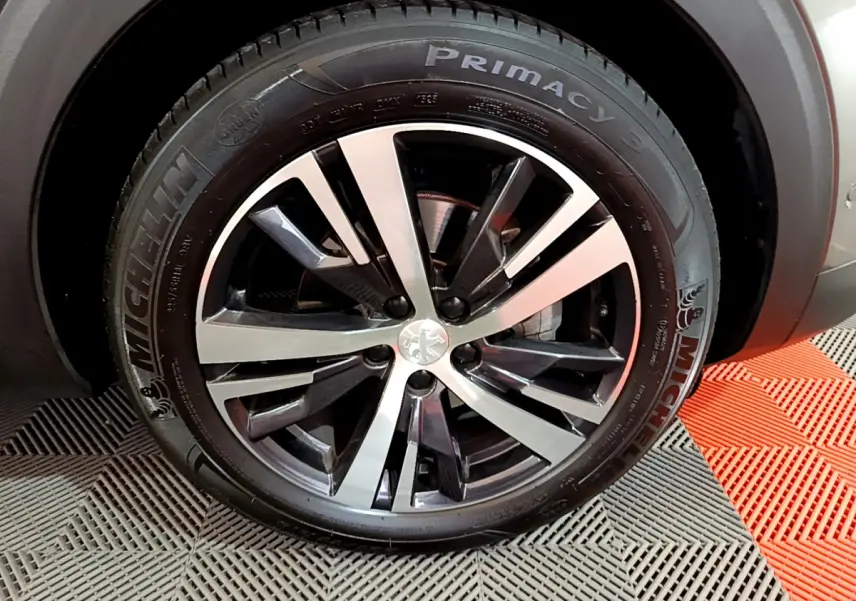 Gros plan sur la jante alliage bicolore et pneu Michelin d'un Peugeot 3008 gris clair, côté avant droit.