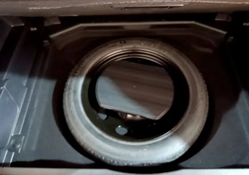 Vue plongeante sur la roue de secours noire dans le coffre du Peugeot 3008 gris clair 2020.